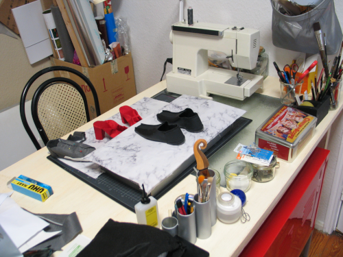 Arbeitstisch mit rotem Unterschrank und mit Objekt in Entstehung, Materialien und Nhmaschine im Hintergrund
